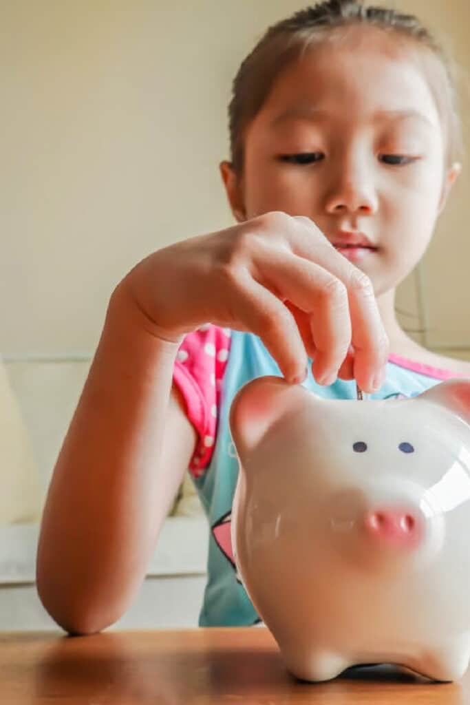 girl putting money in a piggy bank