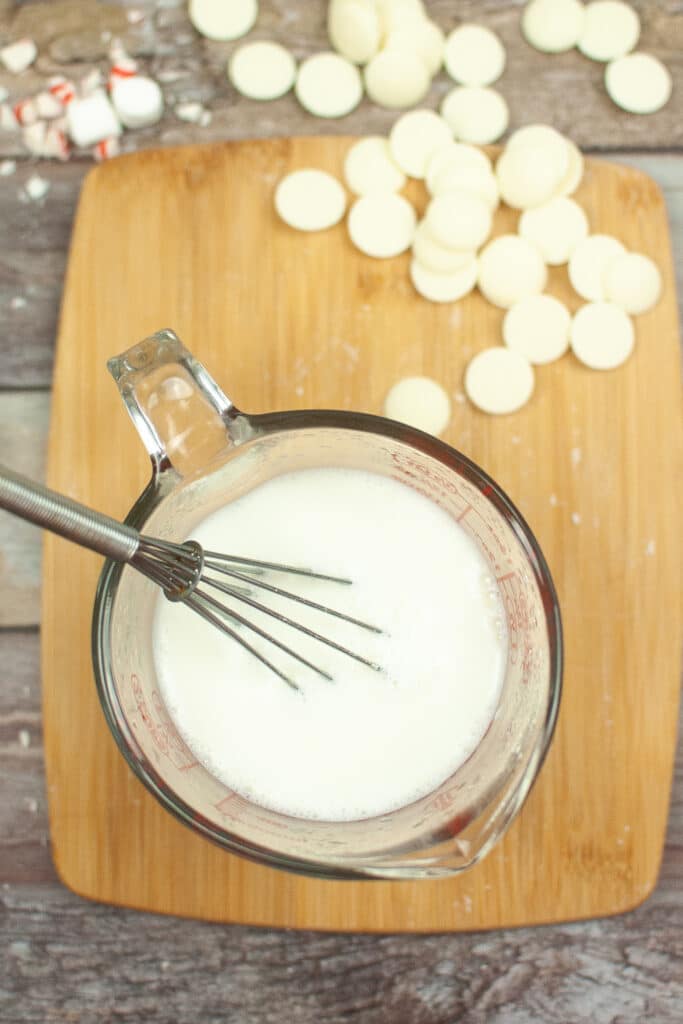 warm milk for hot chocolate in measuring cup with whisk