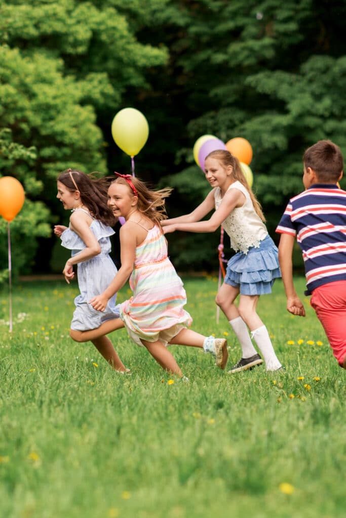 Kids playing party games outside with balloons