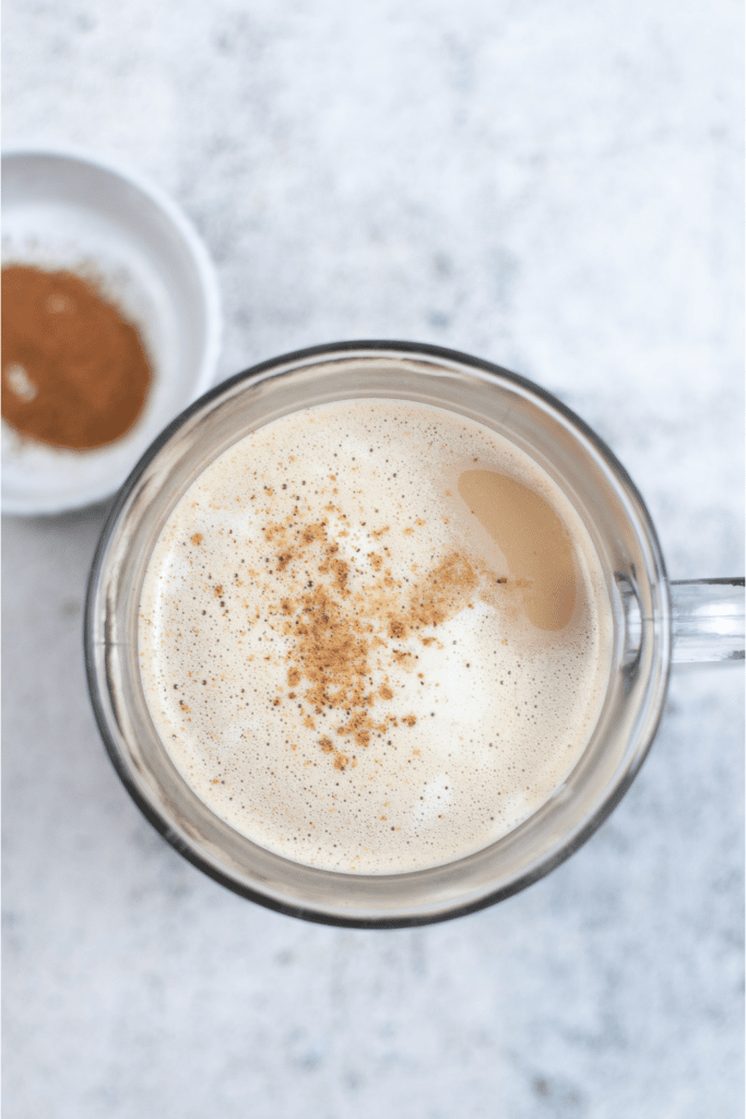 sprinkling cinnamon on eggnog latte