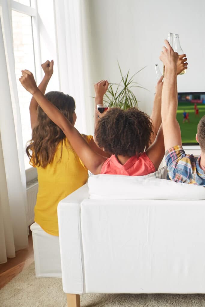 Watching super bowl - people on sitting on couch together in front of tv