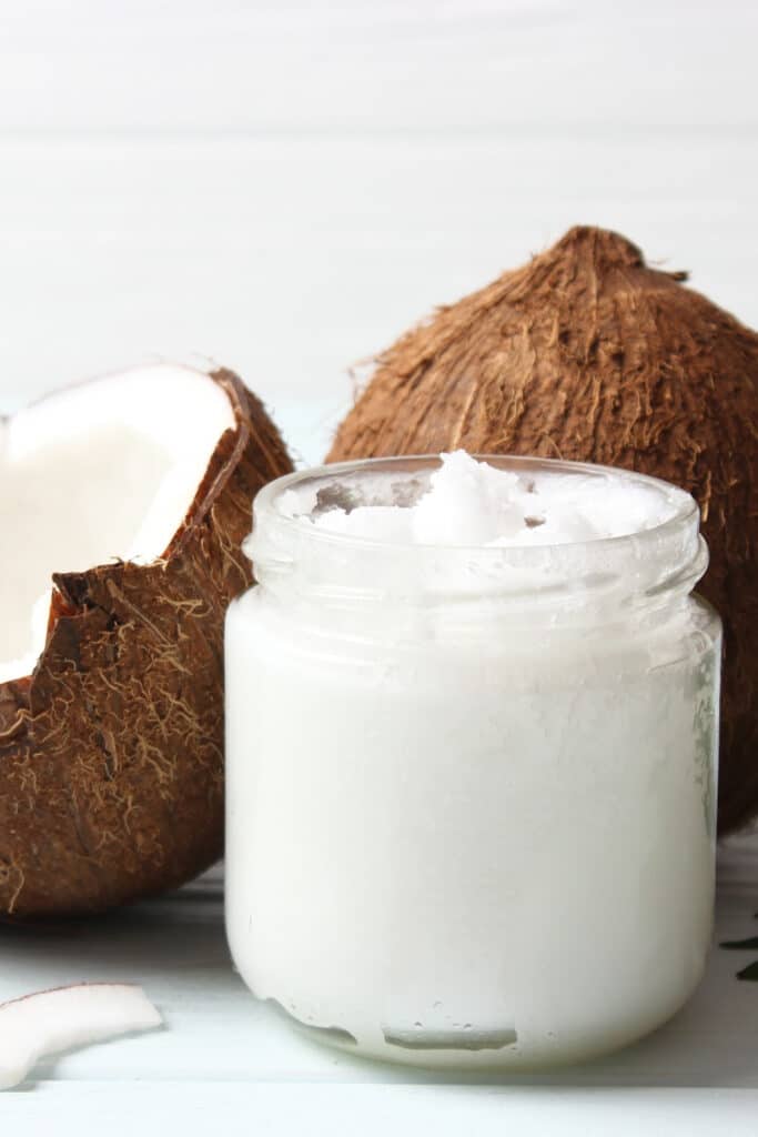 coconut oi uses and benefits - pictured small glass jar filled with coconut oil