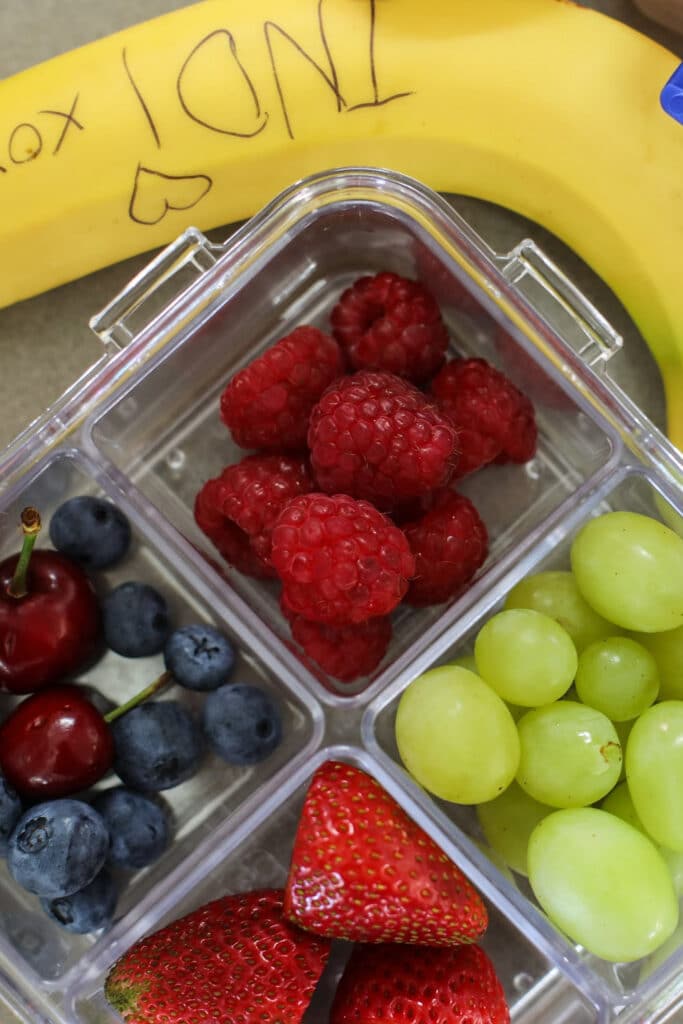 healthy snacks - bento box filled with different types of berries - blueberries, green grapes, raspberries and cherries