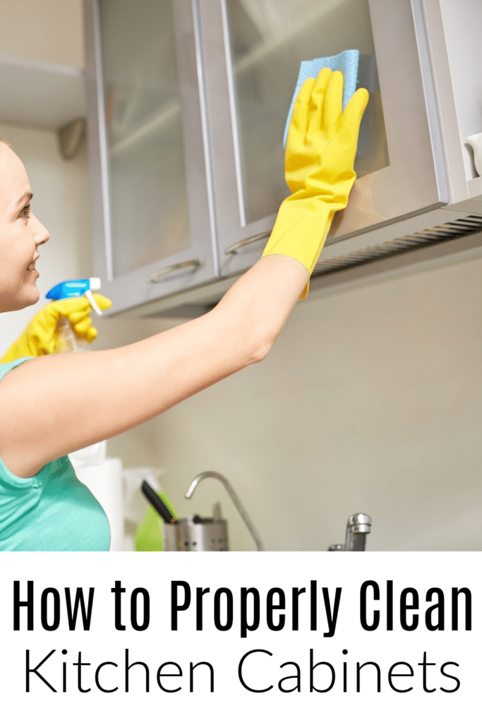 how to clean kitchen cabinets - woman with cleaner wiping down kitchen cabinets to remove grease