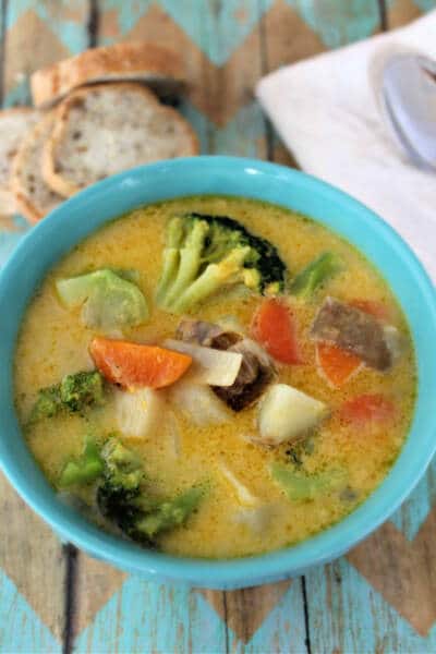 Cheesy vegetable soup in serving bowl with fresh cut bread