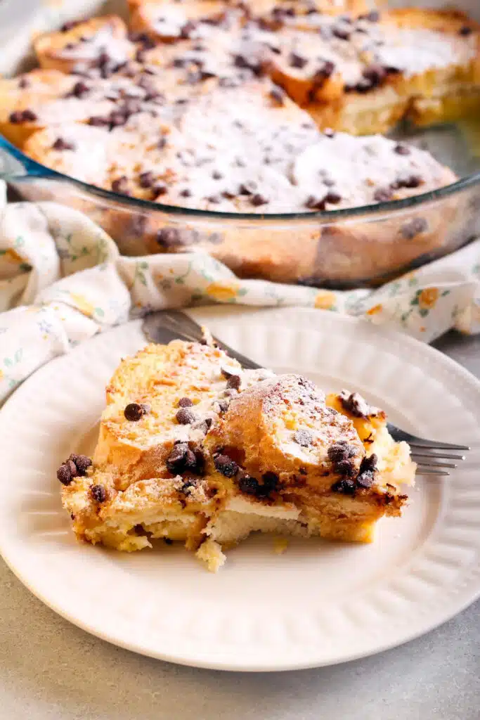 bread pudding with chocolate chips on white plate with a fork