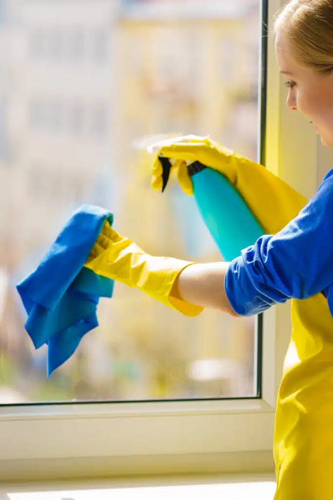 woman cleaning window with glass cleaner