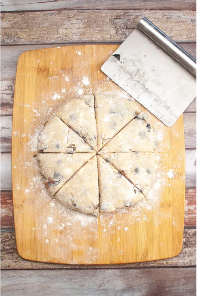 Cutting circular dough on floured surface into wedges