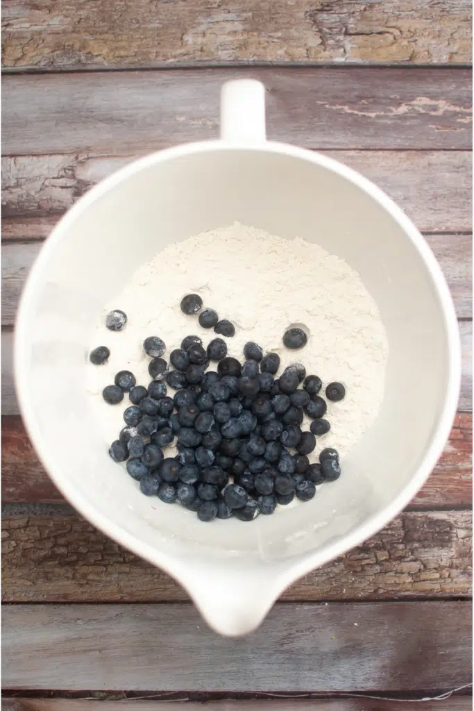 adding in fresh blueberries in too mixing bowl with flour mixture