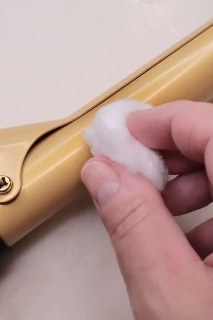wiping curling iron down with rubbing alcohol on cotton ball