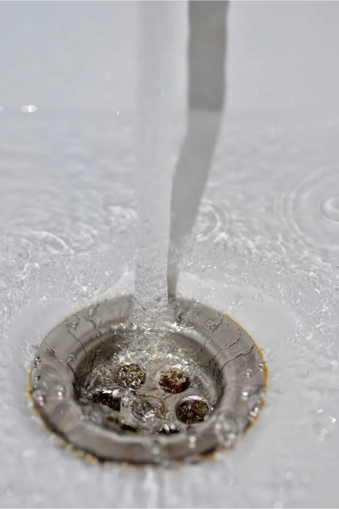 Pouring water down shower drain to check if it is a clogged drain