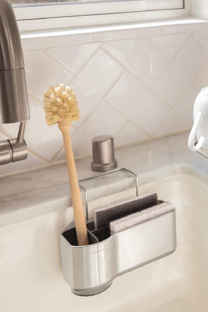 Stainless steal sponge caddy by simpleHuman resting on the inside of sink