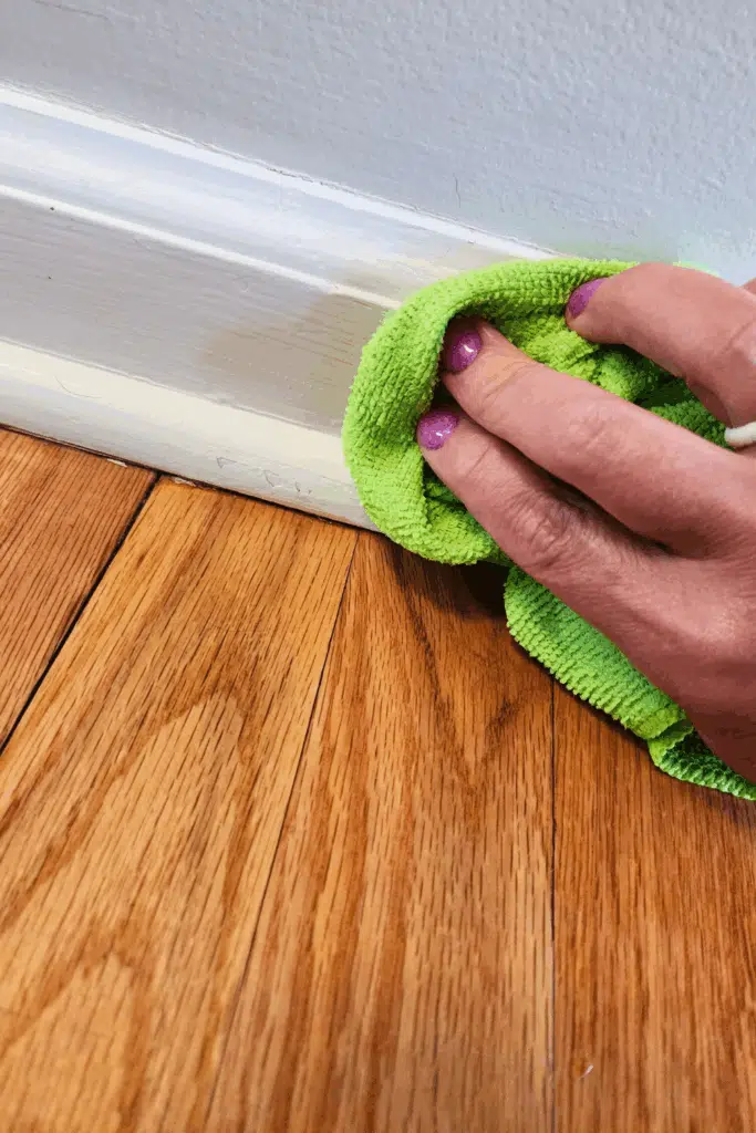 Wiping baseboards with wet microfiber cloth